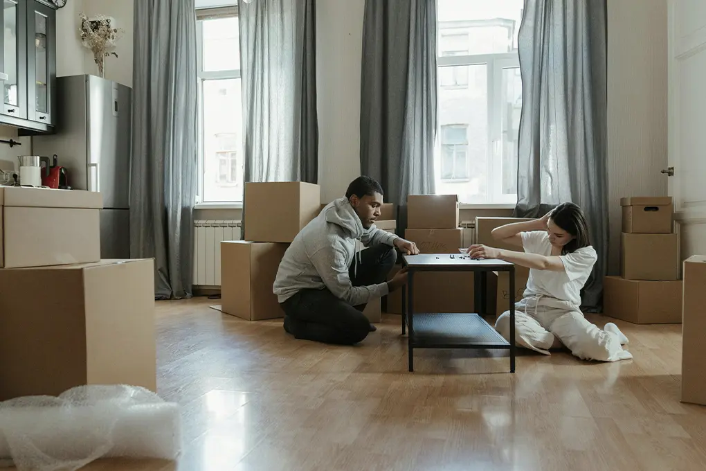 Couple sitting on the floor surrounded by moving boxes, planning and discussing their next steps in a new apartment