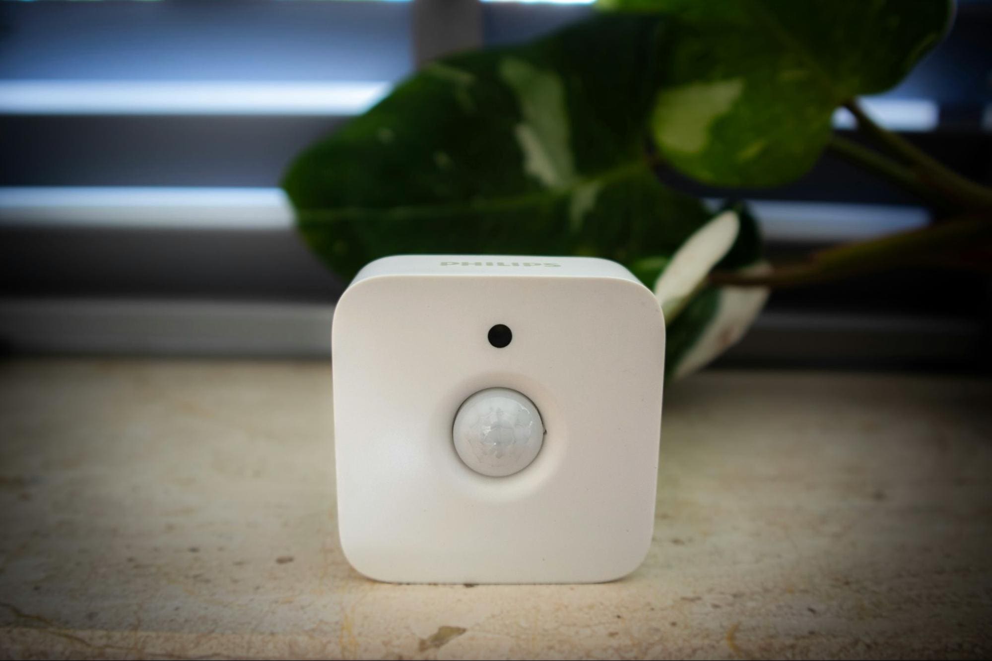 A white, square-shaped Smart Home sensor sits on a beige surface